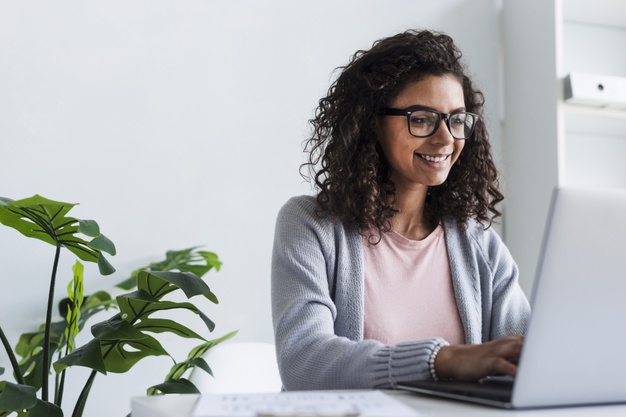 sorrindo mulher jovem trabalhando em laptop em escritorio