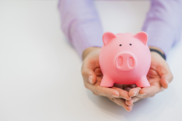 Businessman in a suit holding pink piggy bank with both hands, i