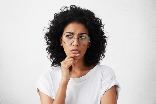 retrato isolado de mulher jovem e elegante de raca mista com cabelo escuro e desgrenhado tocando seu queixo ()