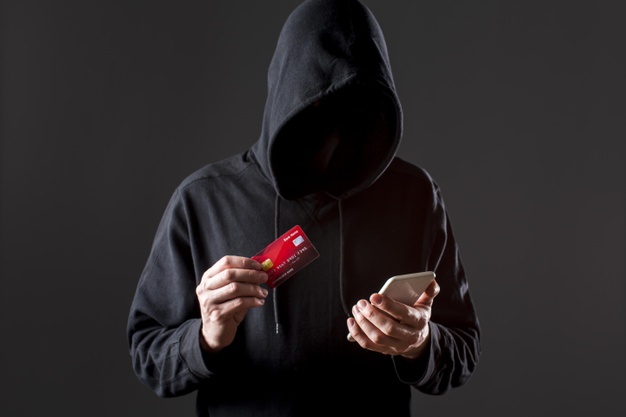 vista frontal do hacker masculino segurando o smartphone e cartao de credito