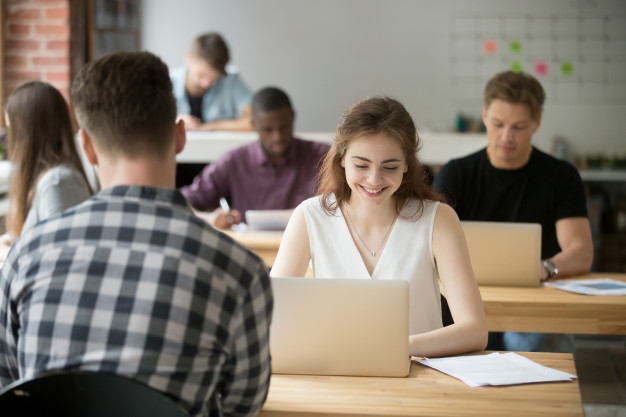 jovem mulher sorridente trabalhando no laptop no espaco de escritorio de coworking