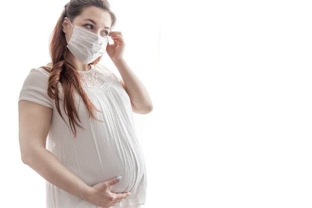 a futura mae de camiseta branca com mascara protetora contra o coronavirus no rosto