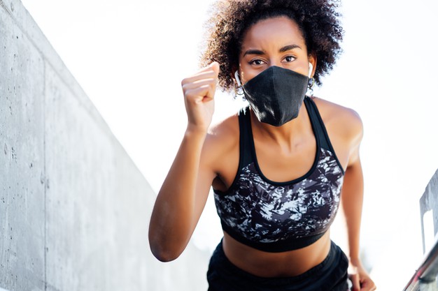 mulher afro atletica usando mascara facial enquanto corre ao ar livre novo estilo de vida normal esporte e conceito de estilo de vida saudavel