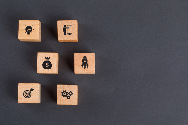 conceito da ideia do negocio com icones em cubos de madeira na configuracao cinzenta escura do plano da tabela