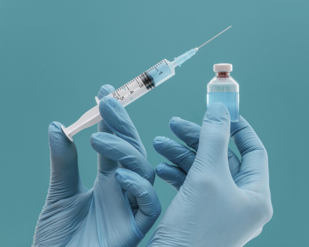 frasco de vacina e seringa segurados por medico com luvas