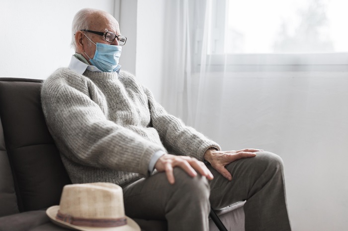 man with medical mask sitting in a nursing home