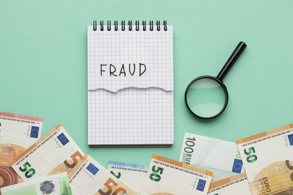 fraud word written on notepad with banknotes