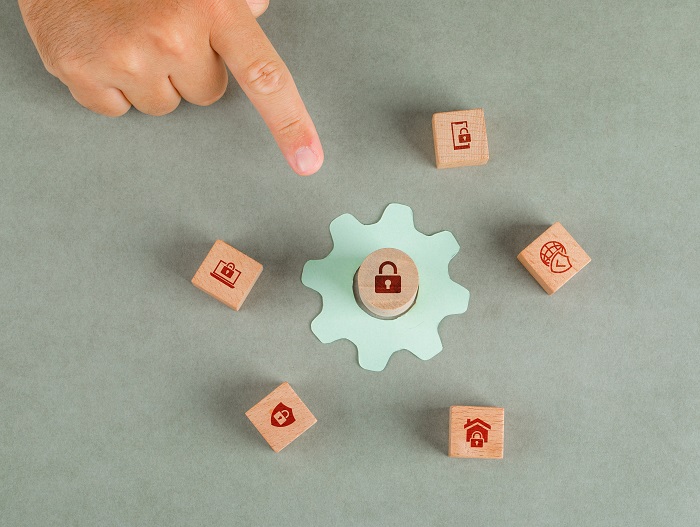 Conceptual of data privacy man hand pointing with wooden blocks, paper settings icon on sage color background flat lay horizontal image
