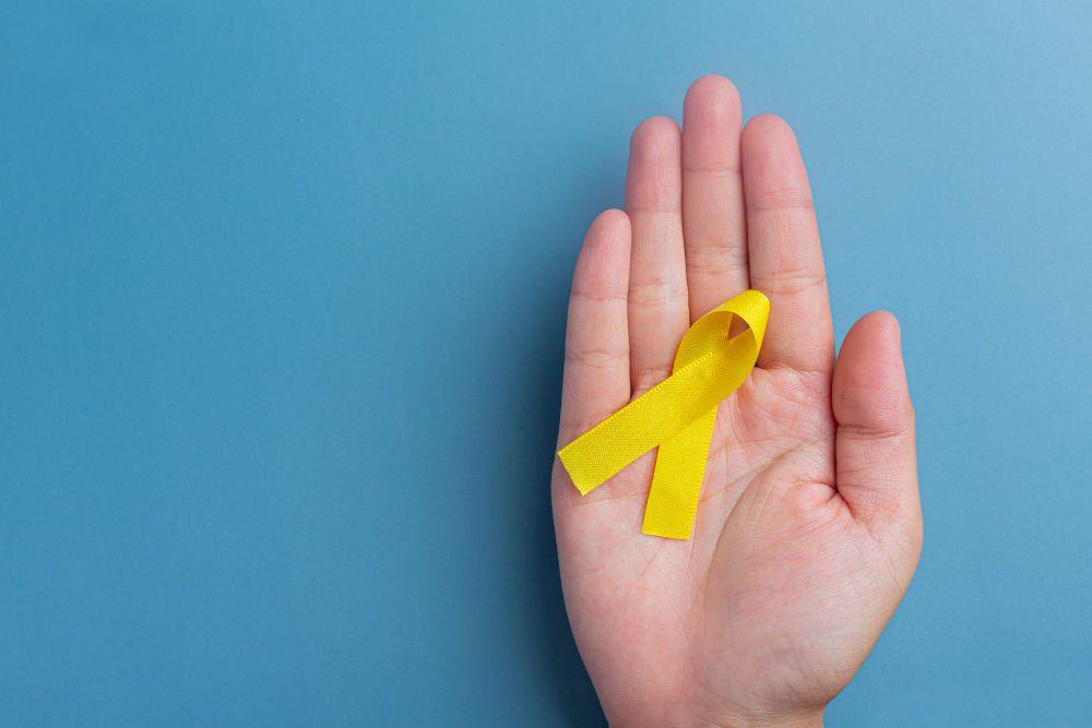 hands holding yellow ribbon symbol of cancer awareness medical support and prevention with helping hand