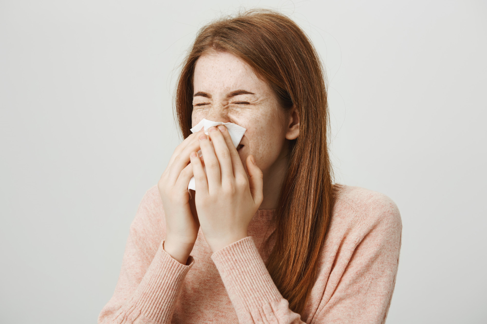 cute sick redhead girl with allergy sneezing in napkin