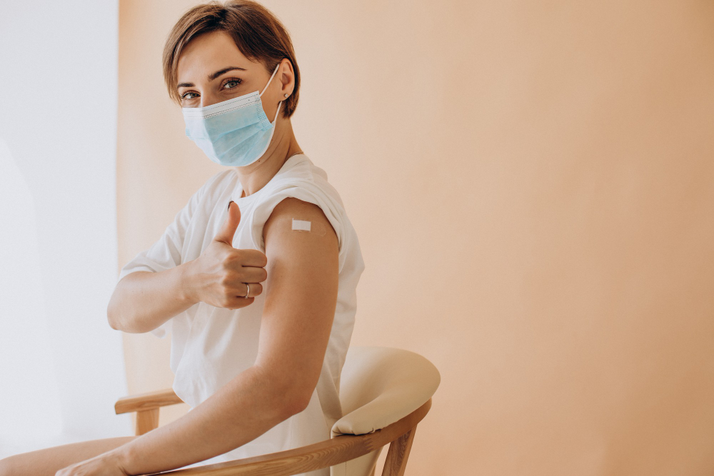 woman with plaster on shoulder sitting in chair after vaccination