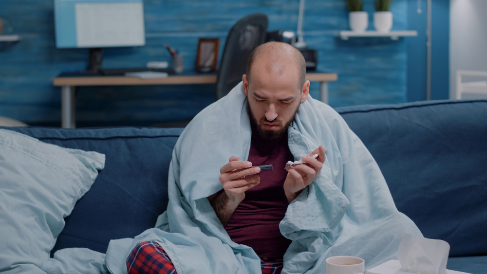 unwell man holding tablets with capsules in hand