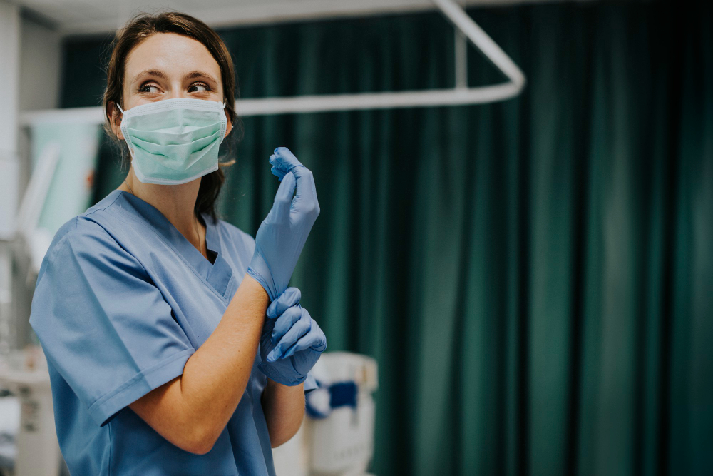 female nurse with a mask putting on gloves