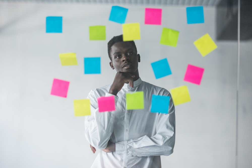 young business man standing in front of stickers glass wall and looking on futures plans at his office place