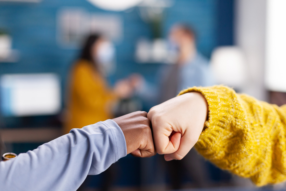 close up of african woman and friend doing fist bump greeting each other in hme living room keeping social distancing as safety precaution during global pandemic with coronavirus