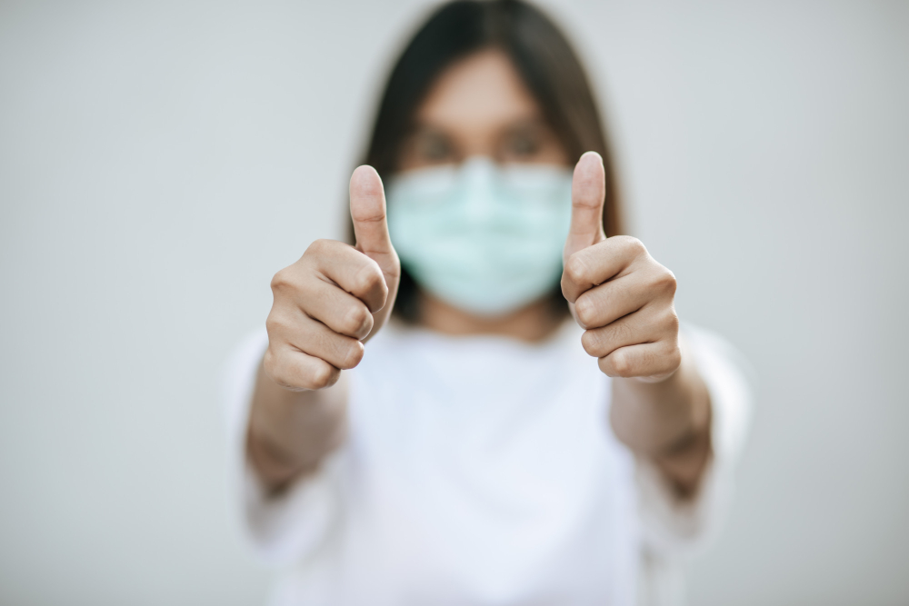 the women wear masks and mark them with their thumbs up