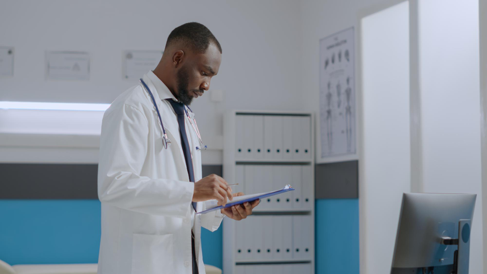 african american specialist doctor checking sickness report documents analyzing medical expertise on computer while working at healthcare treatment in hospital office medicine service
