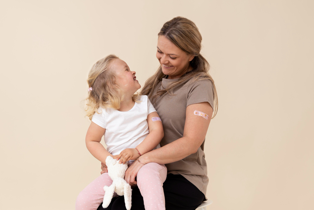 mother and daughter showing sticker on arm after getting a vaccine