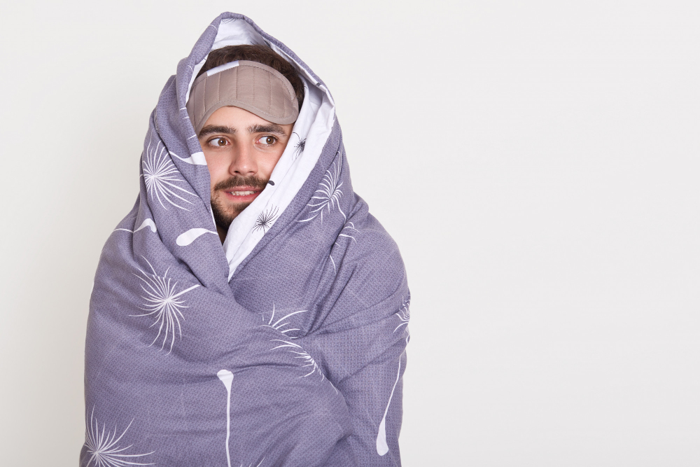 bearded guy with sleeping mask on forehead looking aside being wrapped in blanket copy space advertisement or promotion text