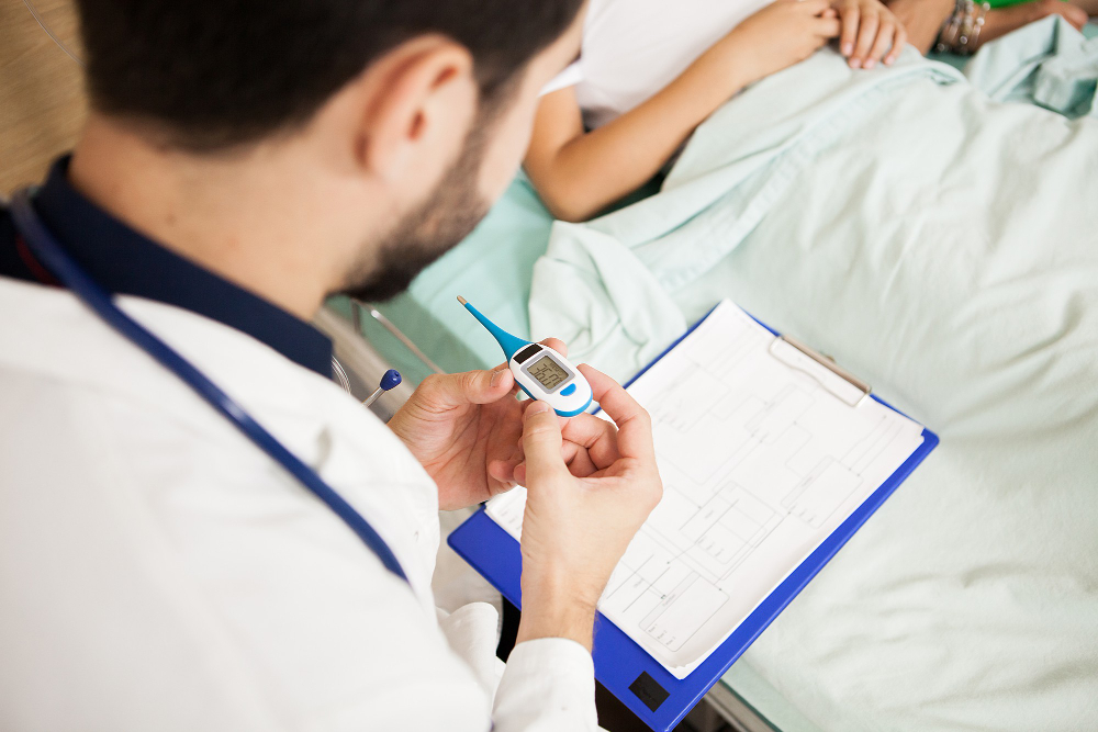 doctor taking body temperature of her patient in hospital room