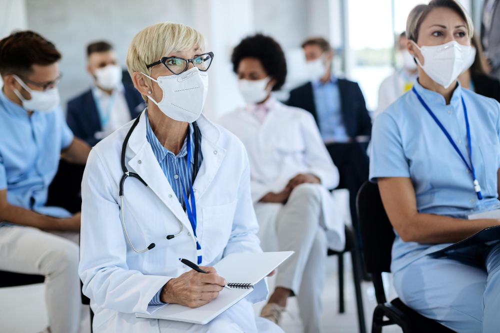 mature healthcare worker taking notes in her notebook during a seminar in board room