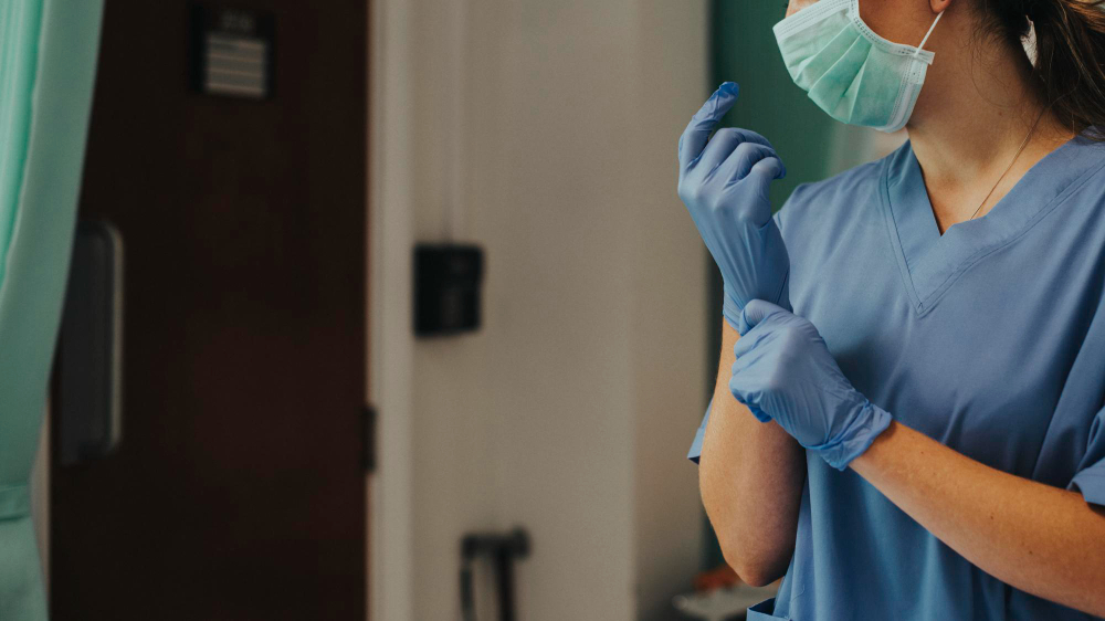 doctor putting on a glove to prevent coronavirus contamination