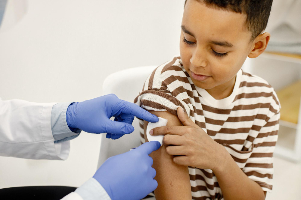 male doctor holding a cotton on a boy s shoulders after a vaccination