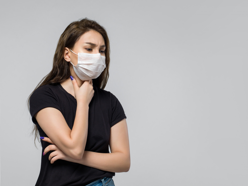 woman wearing black t shirt and medical protective mask feeling sick