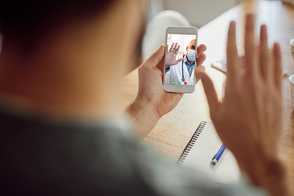 closeup of african american doctor greeting his patient during video call over mobile phone