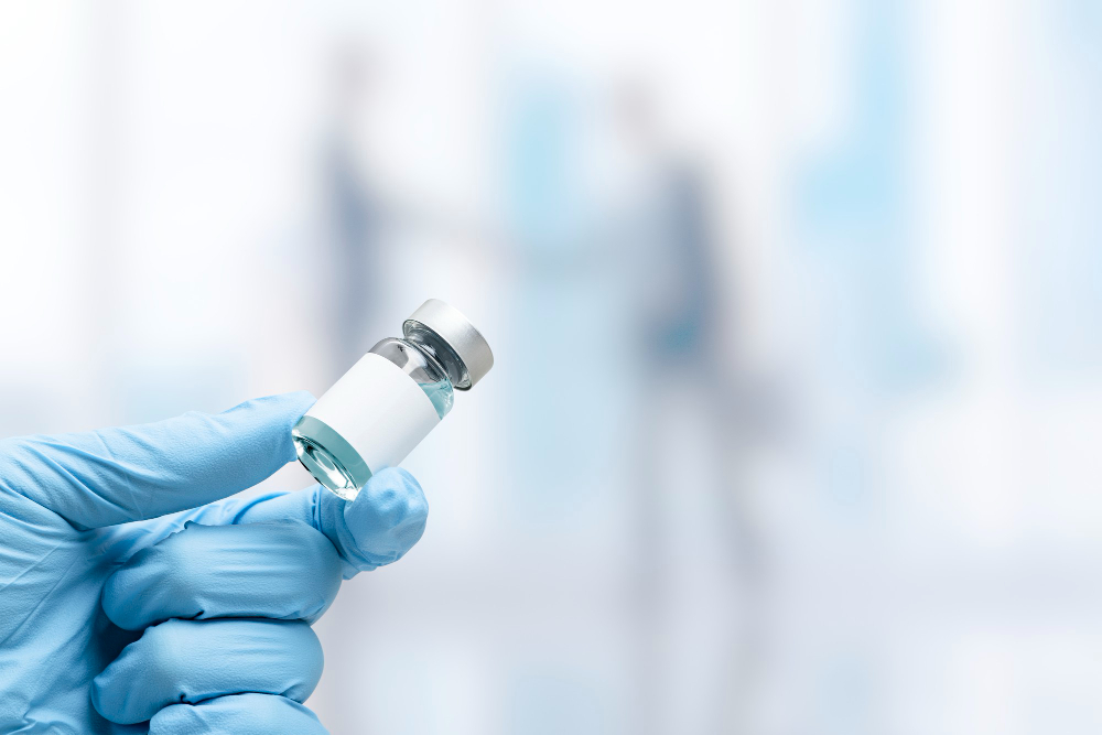 hand in medical glove holding a vaccine vial
