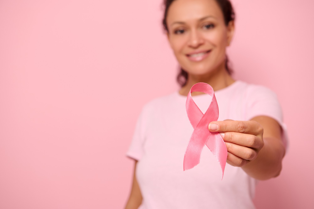 blurred smiling african woman in pink t shirt holding satin ribbon in her hand breast and abdominal cancer awareness october pink day on colored background copy space breast cancer support concept