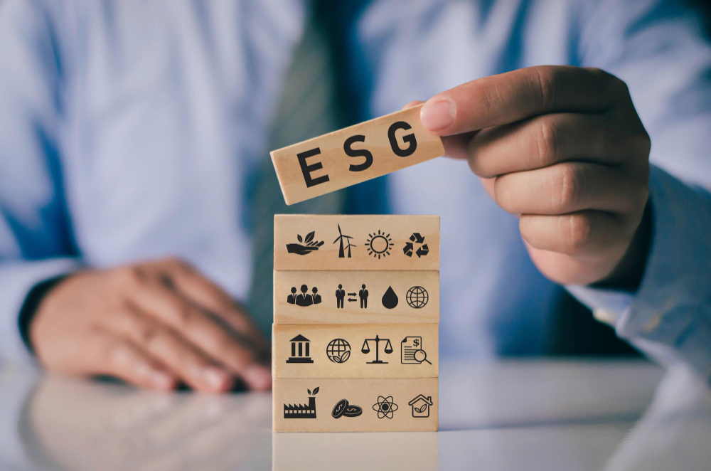 businessman with wooden block on hand esg icon concept for environmental social and governance in sustainable and ethical business on network connection on green background