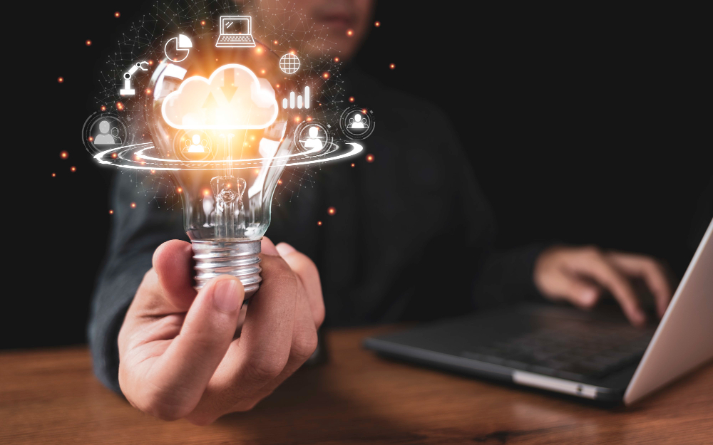 hand holding lightbulb with cloud computing and technology icons such as laptop computer graph cloud technology management big data include business strategy