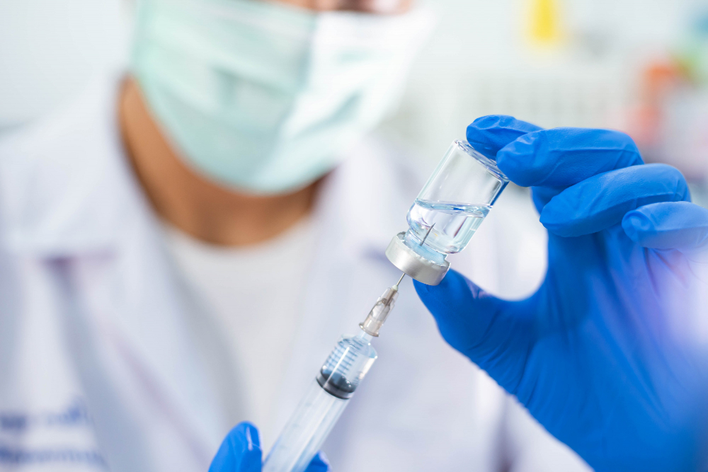 doctor in blue glove filling syringe with vaccine