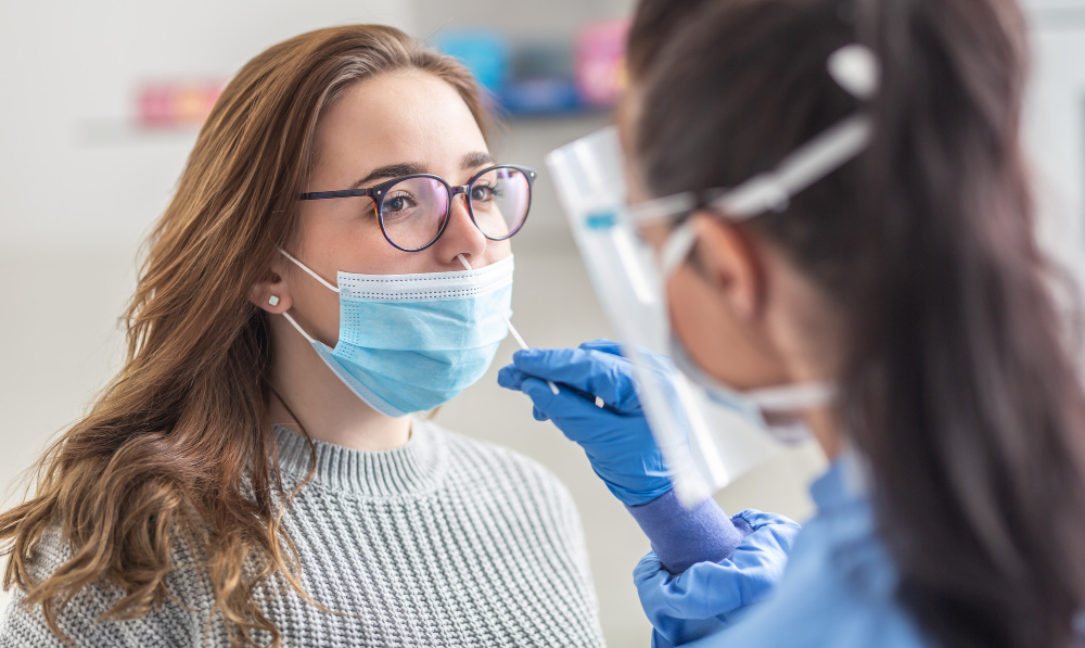 female patient wearing mask over mouth is having sample taken from nose for a pcr test for covid