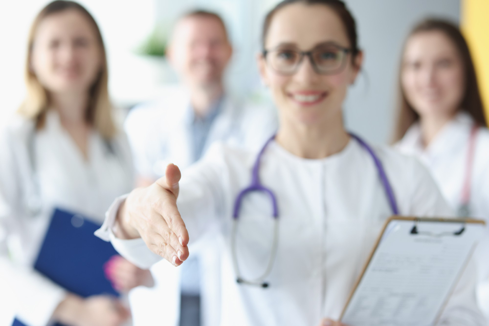 woman doctor stretches out her hand greetings against background medical colleagues