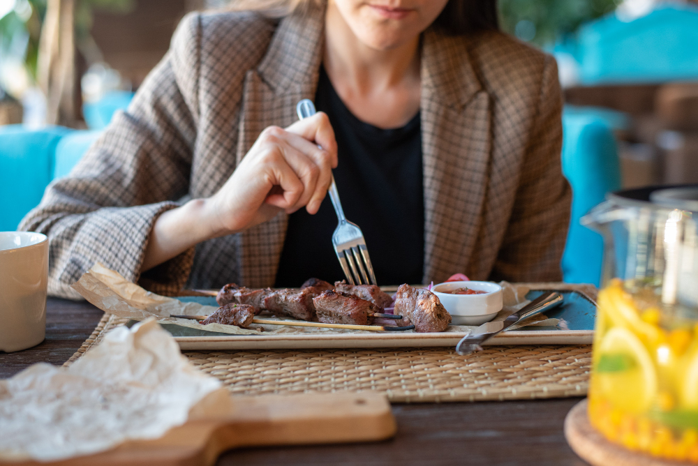 business woman jacket close up restaurant with cutlery eating grilled meat