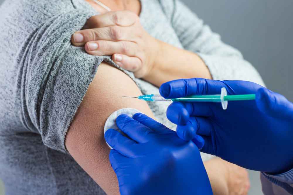 close up doctor s hand wearing blue gloves giving syringe patient s arm