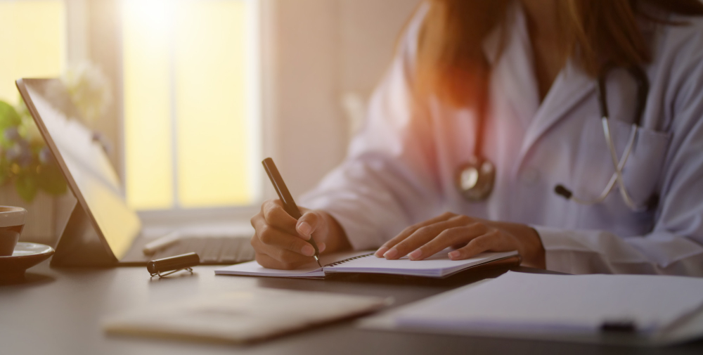 close up view young female doctor writing medical charts with tablet office room