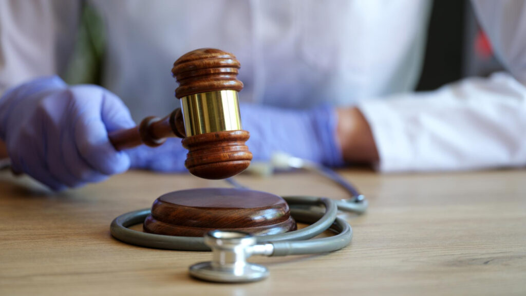 closeup woman doctor hands gloves striking with judge gavel medical malpractice personal