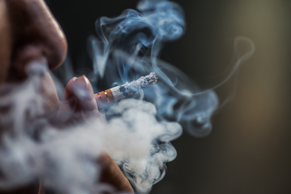 closeup shot person puffing cigarette surrounded with smoke