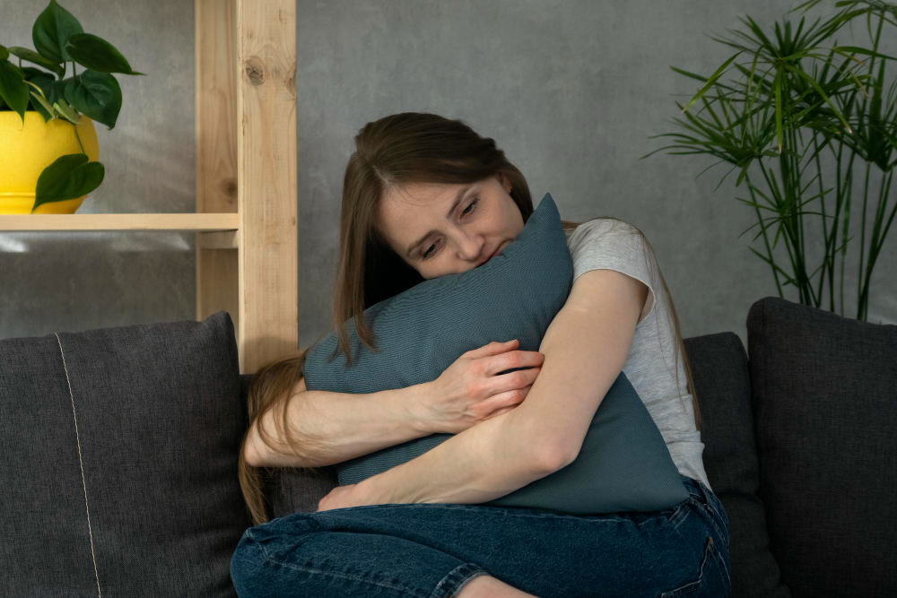 girl hugs pillow while sitting couch young woman is upset lonely