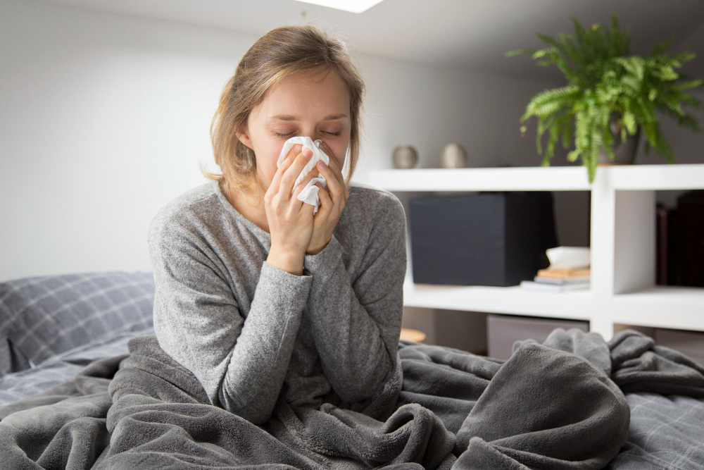 sick woman sitting bed blowing nose with napkin