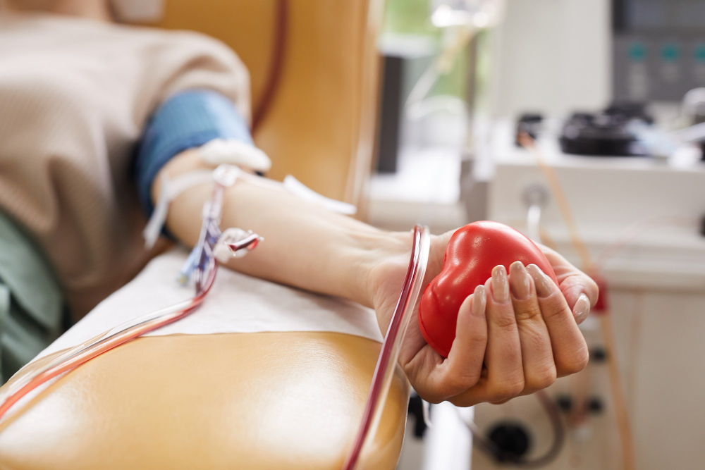 close up patient with tubes her arm squeezing ball her hand while donating blood