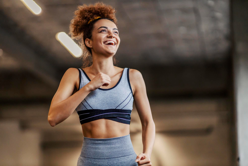 low angle view attractive fit sportswoman with curly hair jogging underground garage