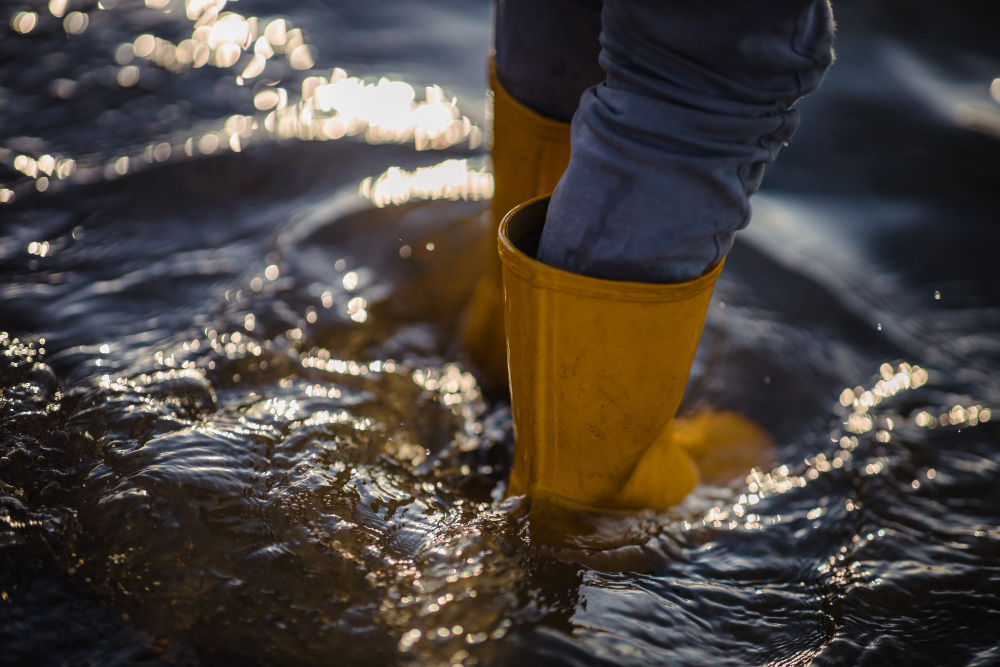person blue denim jeans yellow boots standing water