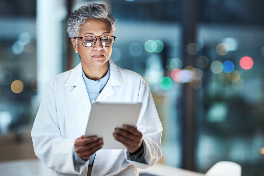 Medical, research and night with doctor and tablet for planning, medicine and schedule Technology, review and digital with senior woman reading report for healthcare, science and life insurance news