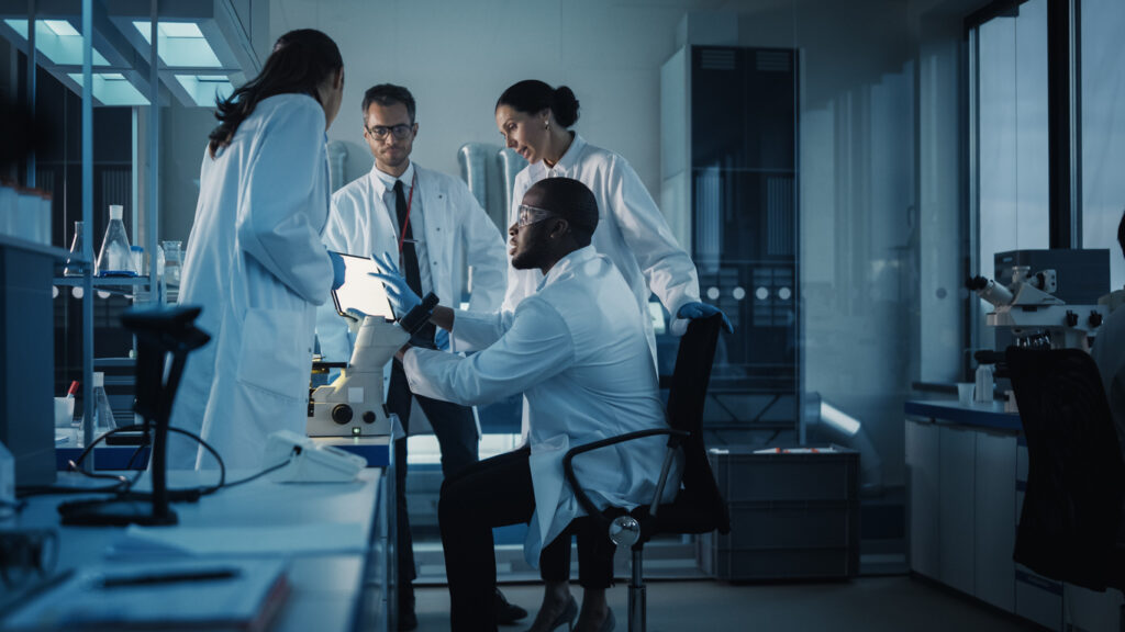 Medical Science Laboratory with Diverse Multi Ethnic Team of Microbiology Scientists Have Meeting on Developing Drugs, Medicine, Doing Biotechnology Research Working on Computers, Analyzing Samples